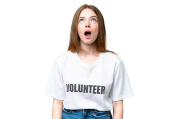 Young volunteer woman over isolated chroma key background looking up and with surprised expression