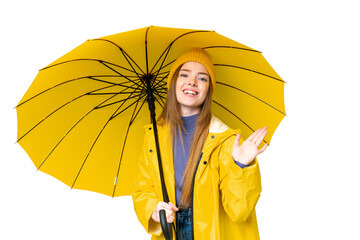 Young pretty woman with rainproof coat and umbrella over isolated chroma key background saluting...