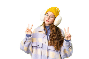 Teenager girl wearing winter muffs over isolated chroma key background showing victory sign with both hands