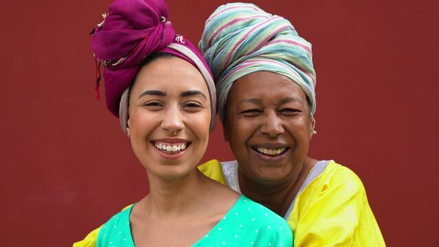 Happy african mother hugging adult daughter while wearing traditional dress and turban	- Family and love concept