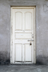 An old white wooden door, bolted and padlocked.