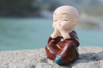 Little buddha or buddhist monk covered his mouth with both hands. Conceptual photo about speech...