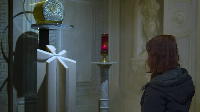 donna prega in chiesa e accende una candela presso un altare