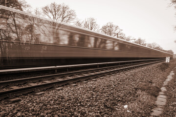 Ein Zug oder eine S Bahn fährt auf einem Gleis. Eine Langzeitbelichtung, Bewegungsunschärfe.