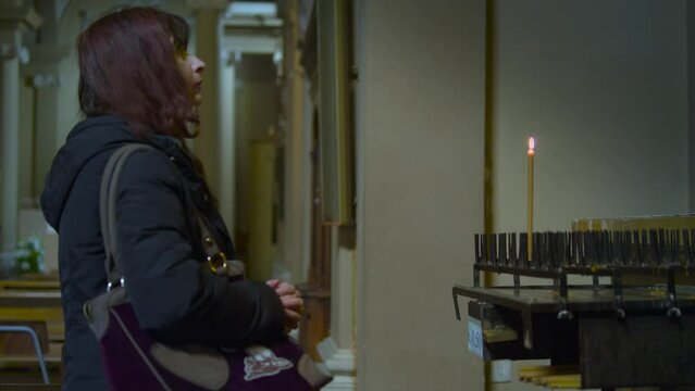 donna prega in chiesa e accende una candela presso un altare