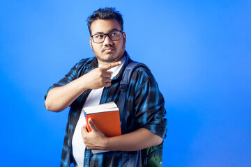 indian student pointing finger against single color background