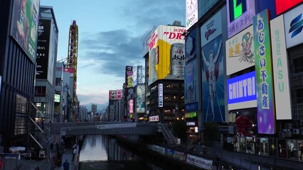 OSAKA, JAPAN : View of Dotonbori area. Tourist destinations, filled with neon signs, clubs and restaurants. Time lapse shot, sunset to night. Logo and signs are blurred or overwritten for this video.