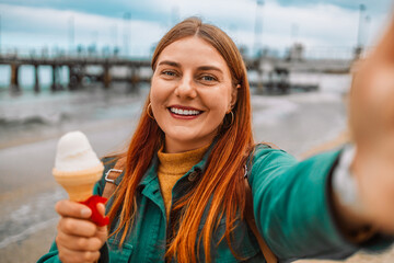 Close up of lovely young girl with ice cream taking a selfie at the beach at Gdansk. Travel,...
