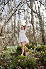 Snowdrops galanthus woman. She stands in a white dress on a meadow with snowdrops in a spring forest