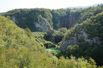 Fototapeta na wymiar Scenic shot of a lake surrounded by cliffs covered in green plants at Plitvice Lakes National Park