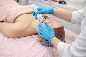 Physician beautician hands in gloves use hydra facial peel machine. Facial beautification procedure in spa clinic center