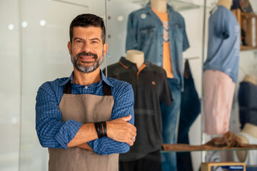 Fototapeta na wymiar Entrepreneur looks at camera and smiles in clothing store.