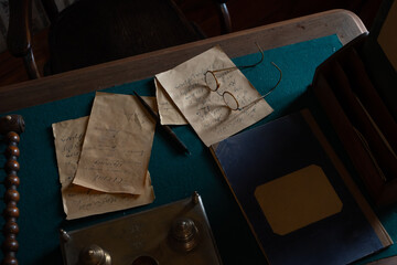 Old yellowed papers or letters on a wooden desk with a pen or pen and glasses. Old office for...