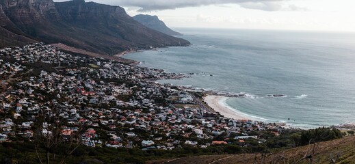 Fototapeta premium Cityscape view from a mountain of Camps Bay houses by the sea in Cape Town, South Africa
