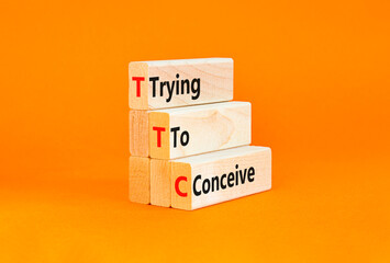 TTC trying to conceive symbol. Concept words TTC trying to conceive on wooden blocks on a beautiful orange table orange background. Medical and TTC trying to conceive concept. Copy space.