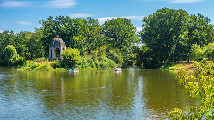 Biggest city park Rotehorn in Magdeburg,and inner lake with people enjoying sunny summer day - obrazy, fototapety, plakaty