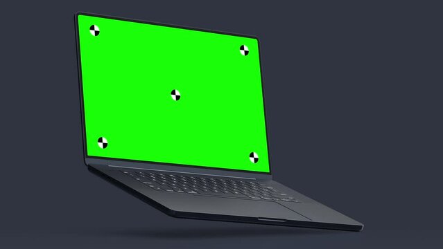 3d render of laptop moving in a dark studio with green screen with marks for tracking