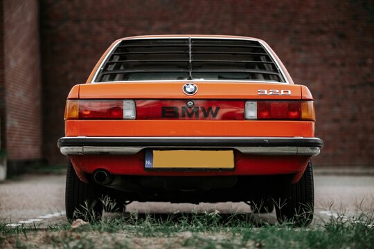 Close-up shot of the back of an orange classic retro BMW 320  car at a parking