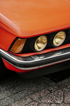 Vertical shot of the yellow headlights of an orange classic retro BMW 320  car