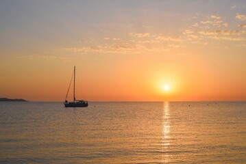 Sea with a sailboat against the beautiful background of the sky at sunset.