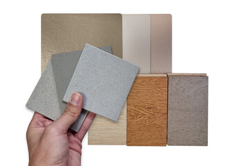 architect's hand holds stone tiles compare color with multi wooden laminated flooring tiles and multi color of leather laminated samples isolated on background with clipping path for selection.