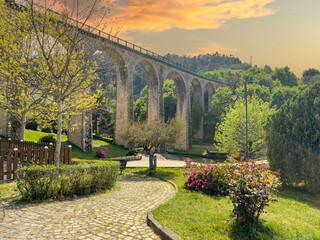 Old railway bridge and garden in Vouzela, Viseu, Portugal, on a sunny afternoon. - obrazy, fototapety, plakaty