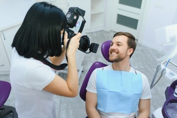 Female dentist photographs her patient's teeth in a dental chair.