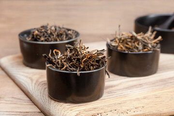 Dry tea leaves in a brown bowls on a wooden board. Dried tea leaves in a bowls on a wooden board. Shallow depth of field
