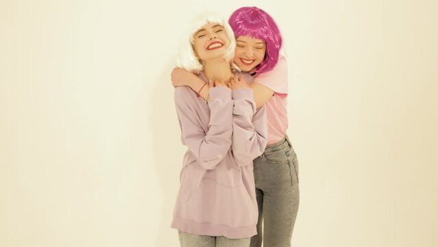 Two young beautiful smiling hipster girls in trendy summer clothes. Sexy carefree women posing in studio near white wall