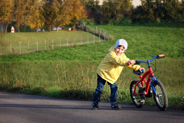 Kid boy of 6 years with bicycle on park road. Healthy lifestyle, environmentally transport concept