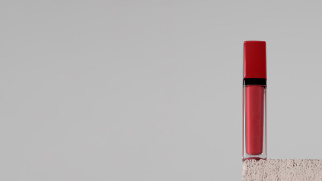 Moisturizing red lip balm on a stone pedestal. Makeup. Copy space. Banner
