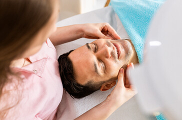 Fototapeta na wymiar Beautician doing face treatment in beauty salon to a man..