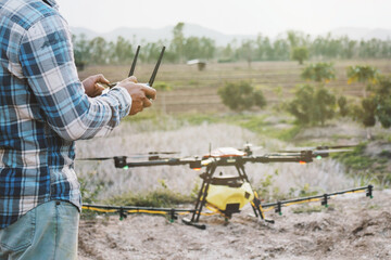 Farmer using drone controller  or drone transmitter a remote control for agriculture sprayer drone in rural area countryside farm