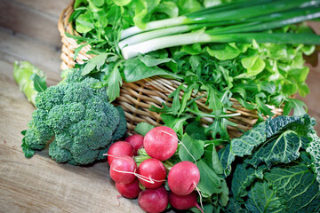 Healthy fresh organic food in springtime, variety of fresh vegetables in a wicker basket on a wooden table - 592630705
