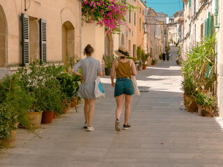 Fototapeta na wymiar Two walking girls on the street in the old town of Alcudia, Mallorca.