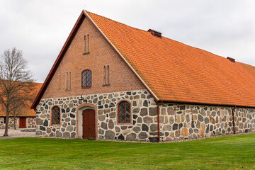 Fototapeta na wymiar An old ancient building in Scandinavian style from big stones and bricks. Rural area, village, big farm.