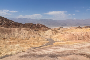 Fototapeta na wymiar Scenic view of Badlands of Zabriskie Point, Furnace creek, Death Valley National Park, California, USA. Erosional landscape of multi hued Amargosa Chaos rock formations, Panamint Range in the back