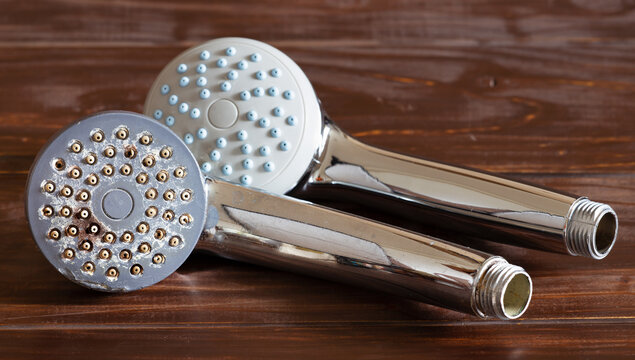 Dirty old shower head with black mold and limescales next to a new one in the bathroom