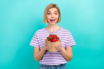 Photo of astonished girl with straight hairstyle dressed stylish t-shirt hold basket of strawberry isolated on turquoise color background