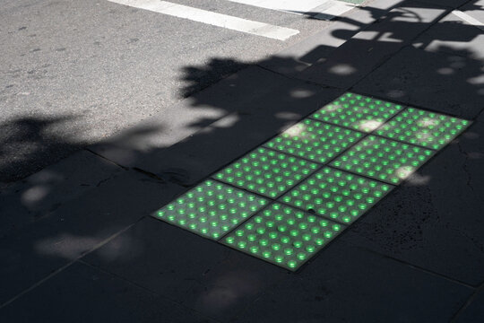 Pedestrian crossing lights embedded in the pavement for phone zombies that never look up at pedestrian crossings in Melbourne, Australia. Bright green square glowing tiles in action - Powered by Adobe