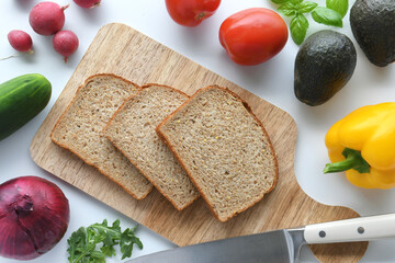 Flat lay of whole wheat bread and colorful vegetables. Preparing to make healthy veggie vegan sandwiches.