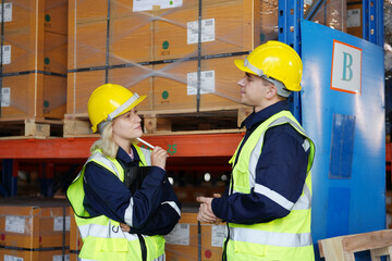 Multiethnic industrial workers checking their logistic lists while working with transportation of goods in warehouse