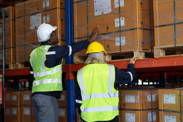 Multiethnic industrial workers checking their logistic lists while working with transportation of goods in warehouse