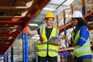 Multiethnic industrial workers checking their logistic lists while working with transportation of goods in warehouse