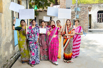 Group of traditional indian woman holding blank cardboard placard protesting yelling in megaphone....