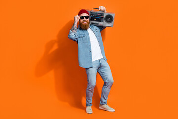 Full length photo of excited funky guy dressed denim jacket listening songs having fun isolated orange color background