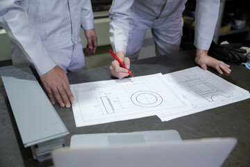 People drawing blueprints of something in a factory no-face