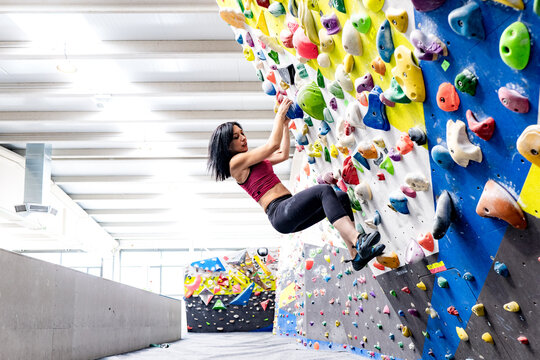 Woman climbing indoor wall with grips