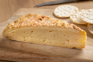 Piece of artisanal Dutch cheese, Round Red, on a cutting board close up for a snack 