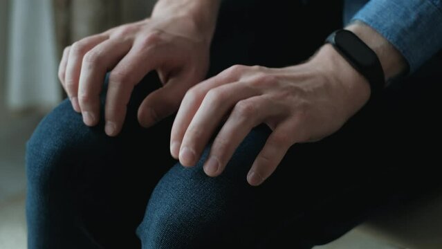 Twitching hands of an impatient nervous man on his knees, close-up